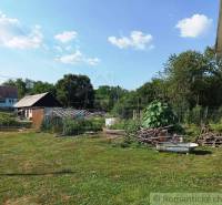 A garden space with a gazebo and a family house, surrounded by nature and sunny weather.