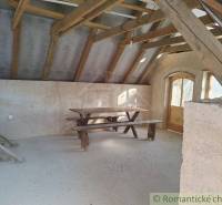 Attic room with a wooden table, benches, wooden beams, and doors, ideal for a cabin.