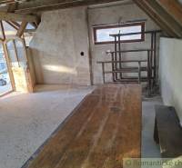 A rustic cottage with a wooden table, bench, and arched door creates a cozy atmosphere.