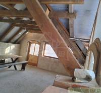 A cottage with wooden beams, benches, a table, a brick wall, natural light.