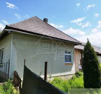 A cottage surrounded by nature with a classic roof and simple fencing.