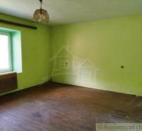 A room with a wooden floor, light yellow walls, and a simple light fixture on top. Cabin.