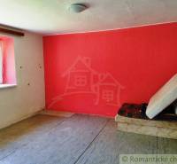 A room in a cottage with a striking red paint and a simple interior.