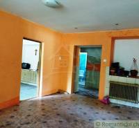 Orange walls in the room, doors leading to the kitchen, a radiator, and a fireplace in the cabin.