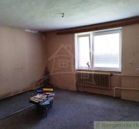 A room with bare walls, a table, and window blinds, suitable for renovating a cottage.