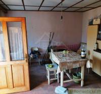 Dining room in a family house with wooden doors, a sofa, and a table with a tablecloth.