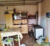 A kitchen in a family house with a classic stove, kitchen cabinets, and a dining table.