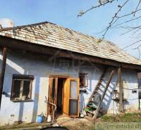 An old house with a wooden roof and an improvised ladder in the countryside.