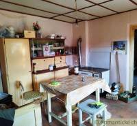 A kitchen in a family house with wooden furniture, a table, and a simple stove.