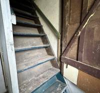 Narrow wooden stairs in an old family house with faded walls.