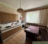 Retro kitchen with a dining table in a family house, warm-colored wallpaper and a large window.