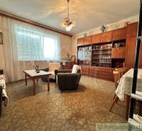 Living room with a wooden wall cabinet, armchairs, and a family house with a carpet.