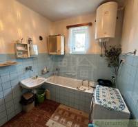Bathroom in a family house with a bathtub, sink, and washing machine, decorated with blue tiles.