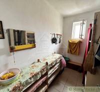 A narrow hallway with a window, a mirror, kitchen utensils, handmade decorations, furniture in a family house.