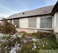 A family house under the snow with large windows surrounded by plants in autumn weather.