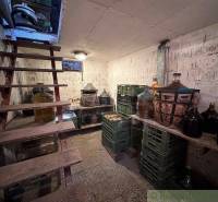 Cellar with wooden stairs, demijohns, and crates of wine for storage in the cottage.