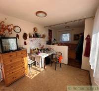The interior of the cabin with wooden furniture, a collection of clocks, a kitchen, and sunlight illumination.