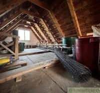 Attic with storage items, ladder, and window, suitable for a cottage or cabin.