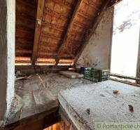 The attic of the cottage with a wooden roof truss and a view from the window of the surrounding landscape.