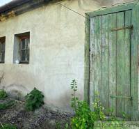 Green wooden door and plastered wall of a country cottage with old windows.