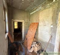 An unrenovated room in a cottage with a chair and building materials.