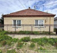 A family house with a brick roof, a fence, and a garden.
