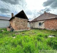 The image shows brick buildings on a plot with tall grass. Family house.