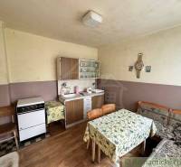 A kitchen unit and furniture with floral tablecloths in an older family house.