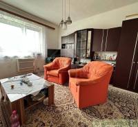 Living room with orange armchairs and a carpet, family house, older furniture.