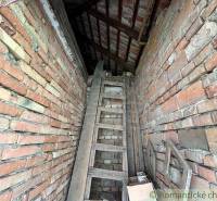 The attic space of a family house made of old bricks, with a wooden ladder leading to the loft.