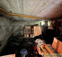 A dark cellar with cardboard boxes, old furniture, and hoses, located in a family house.