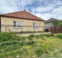 A family house with a fence and a garden, located in the countryside.