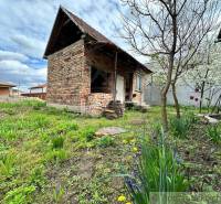 A brick family house with a wooden roof, surrounded by blooming trees and a garden.