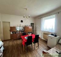 Dining room with a table and chairs, a cabinet, and a family house with a window and a stove.