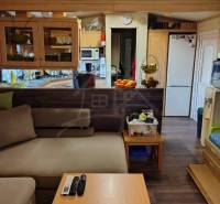 Interior with a kitchen and living room in a family house. Comfortable sofa, refrigerator, dining table.
