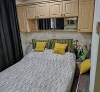 Bedroom in a family house, cozy interior with wooden cabinets and decorative pillows.