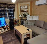 Living room in a family house with a corner sofa, table, and air conditioning vent.