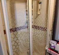 Shower enclosure in the bathroom of a family house, with glass doors and shower accessories.