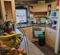 A kitchen with wooden cabinets, a stove, fruit on the table, ideal for a family home.