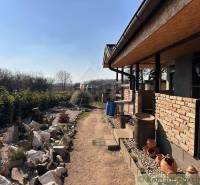 Family house with a brick exterior, stone garden, clay pots, natural surroundings.