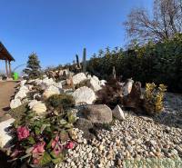 A family house surrounded by a garden with stone elements and colorful plants.
