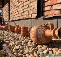 Ceramic jugs and containers decorate the exterior of the family house on a gravel garden.
