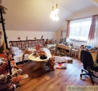 A room in a family house with plush toys, a wooden floor, and a chair by the window.