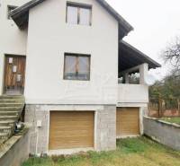 A family house with a white facade, wooden windows, and a double garage entrance.