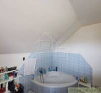 Attic bathroom with a bathtub and shelves in a family house. It exudes coziness and freshness.
