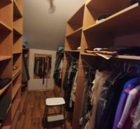 Wardrobe with clothes and a ladder in a family house. Wooden shelves and hangers.