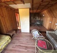 A wooden interior of a cottage with a sofa, a table, and a dining area in a family house.