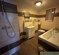 Bathroom with shower and bathtub in a family house with tiles and flooring.