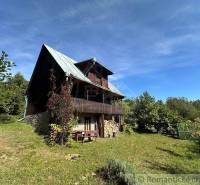 A wooden cottage surrounded by nature with a garden and a bench. A family house in the countryside.