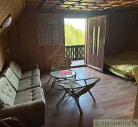 A wooden interior with a sofa, table, and bed creates a cozy atmosphere of a family home.